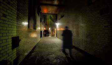 The shadow of a ghost walk guide in an alley in London.