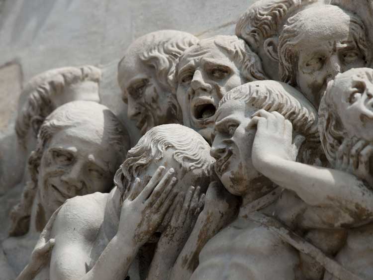 A frieze showing a group of lost souls grimacing.
