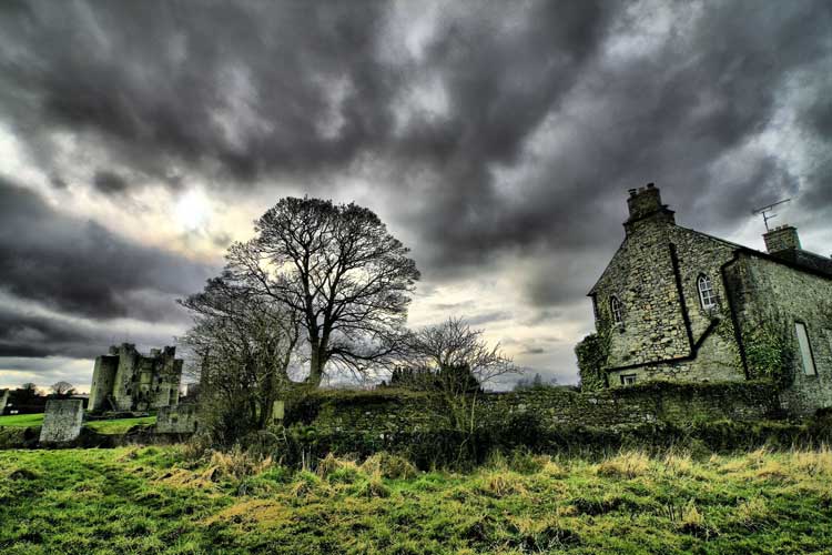 An old house by night with storm clouds overhead.